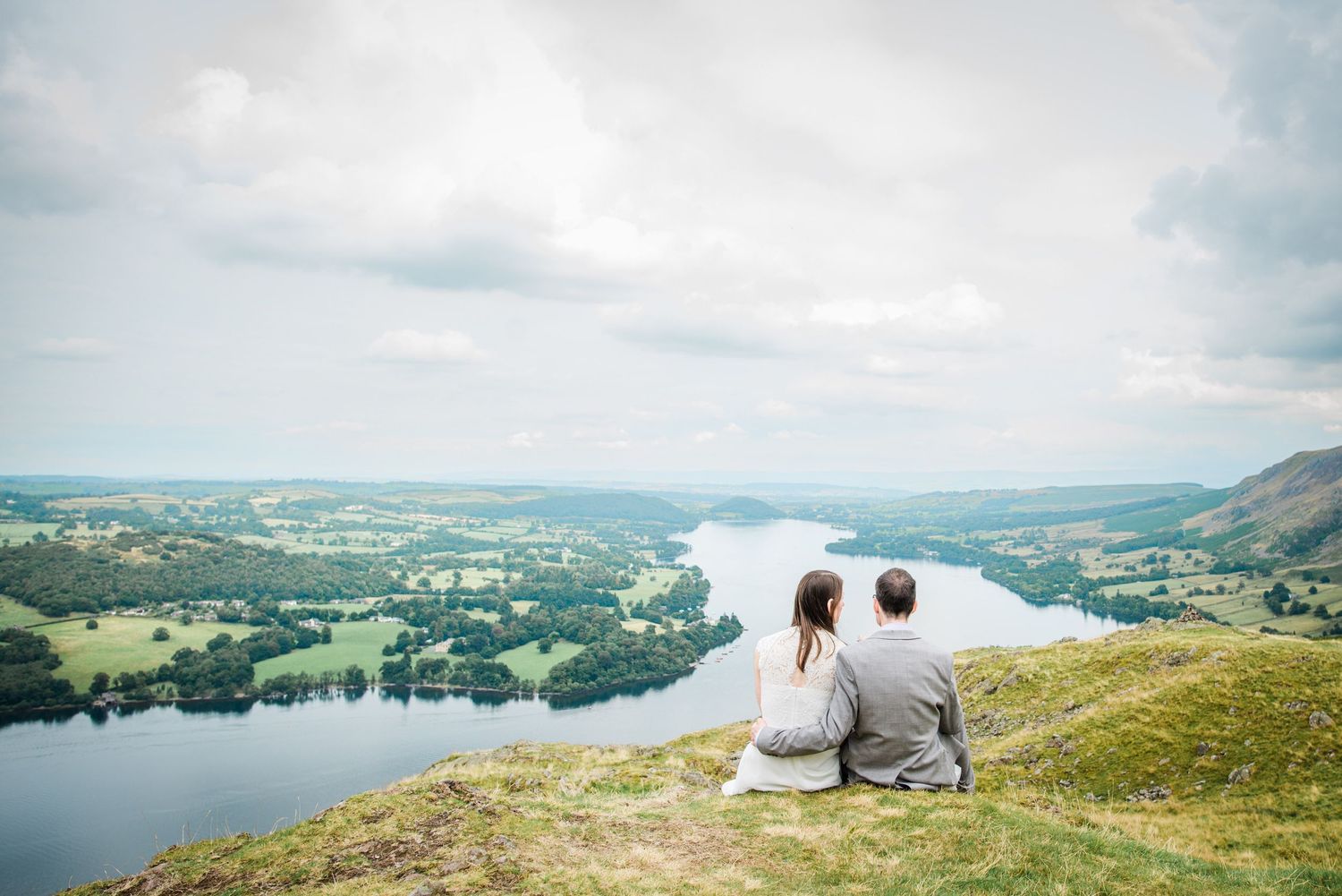 wedding couple sitting on a mountain looking out over Ullswater