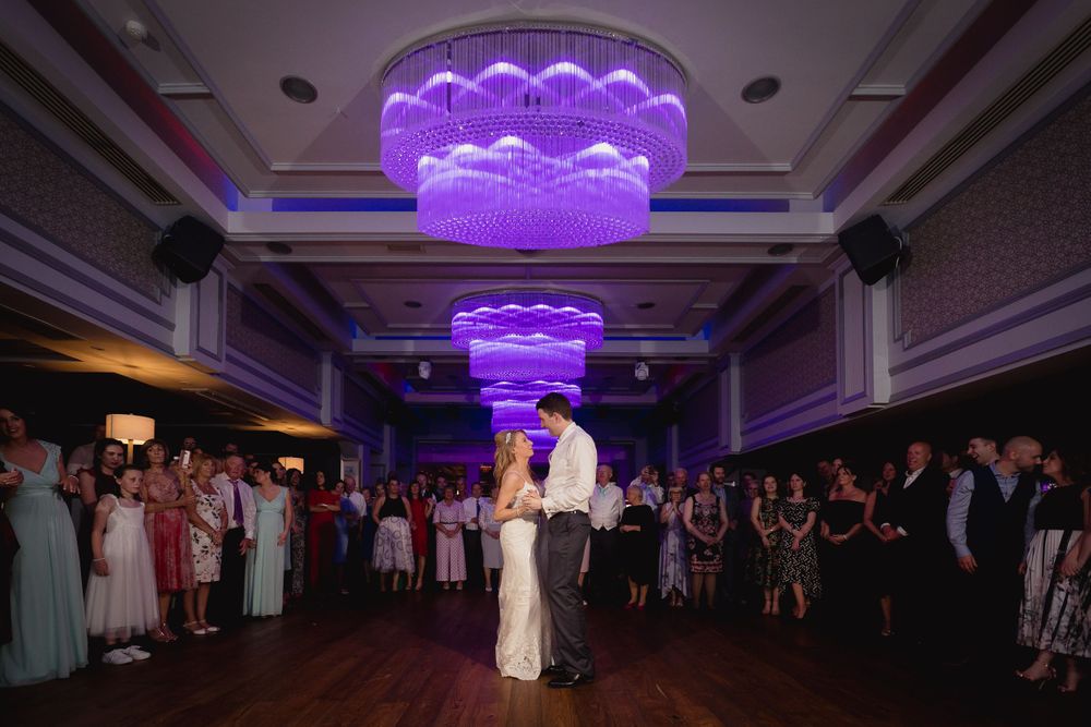Wedding dance under purple LED chandeliers in elegant ballroom.