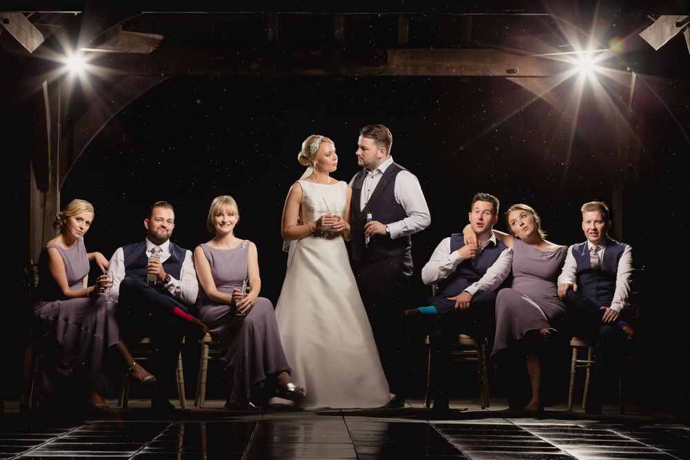 Wedding party seated in an elegant dark venue with dramatic spotlighting.