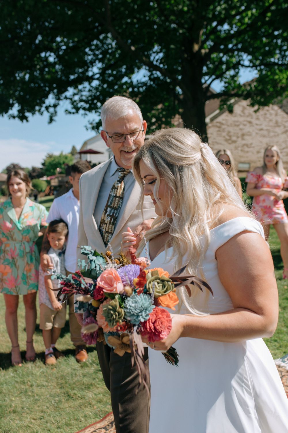 An emotional outdoor wedding scene with vibrant floral bouquet.