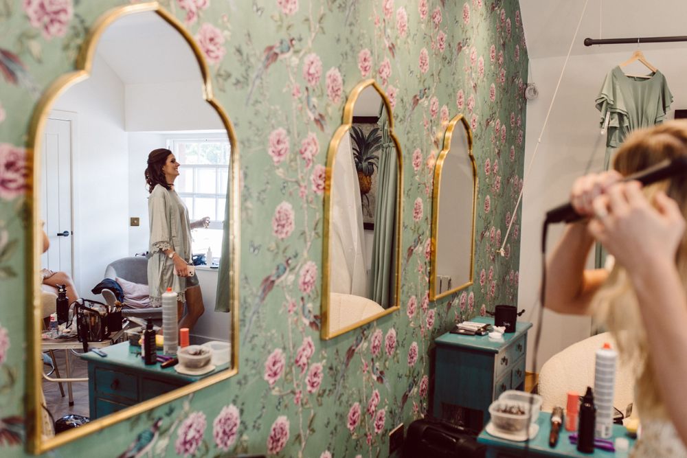 A getting ready room with floral wallpaper and mirrors for wedding preparations.