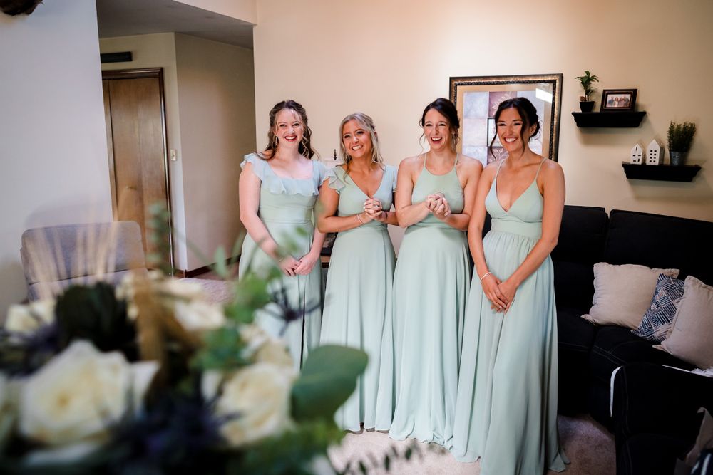 Wedding party wearing mint green bridesmaid dresses gathered in an indoor setting.