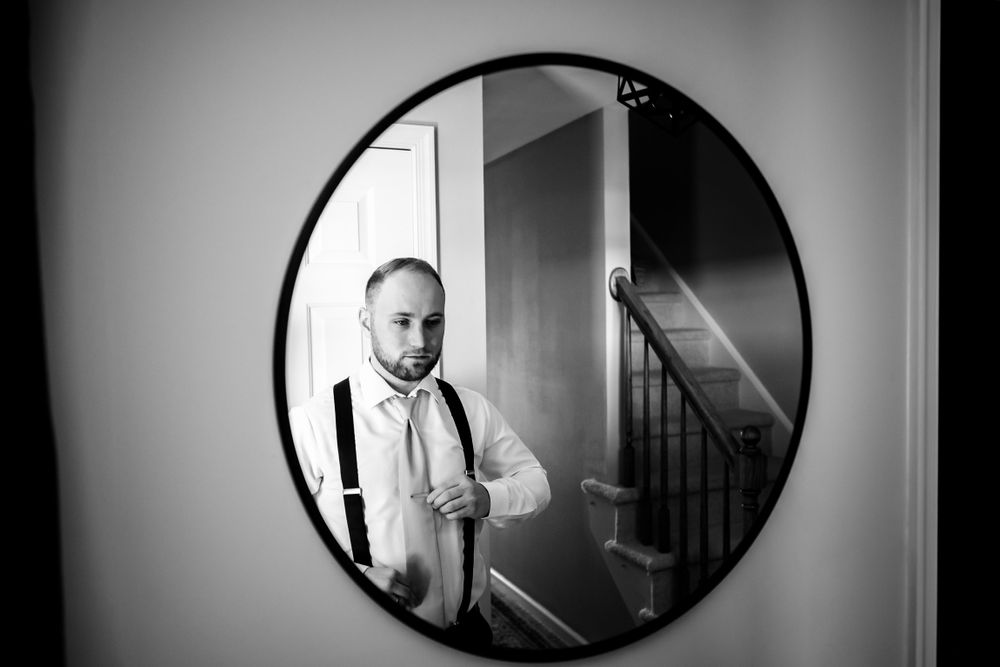 Artistic black and white portraits through oval mirrors showing wedding day preparations.