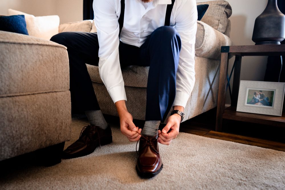 Detail shots of formal brown leather shoes and suit pants during wedding preparations.