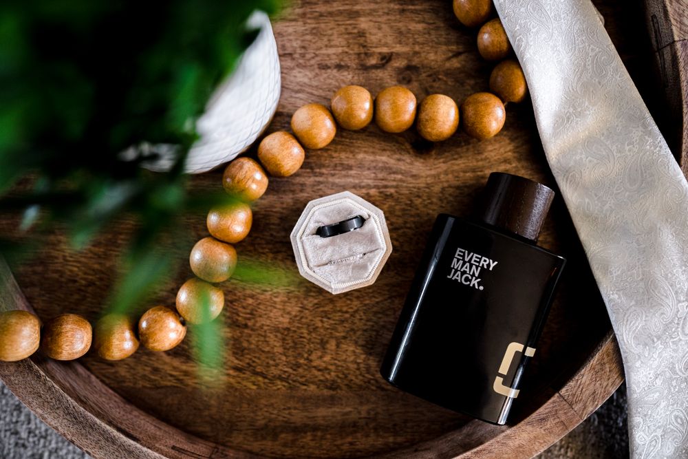 Wedding details with wooden beads and bottles arranged on rustic wooden surface.