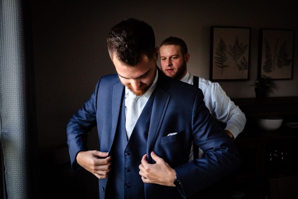 Wedding party members in navy suits and white shirts preparing for formal event.