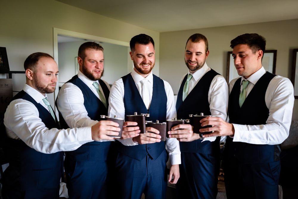 Wedding party members in navy suits and white shirts checking their watches in synchronization.