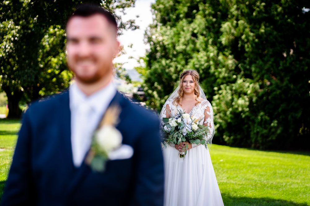 Outdoor wedding photography session with couple and wedding party on sunny green lawn.