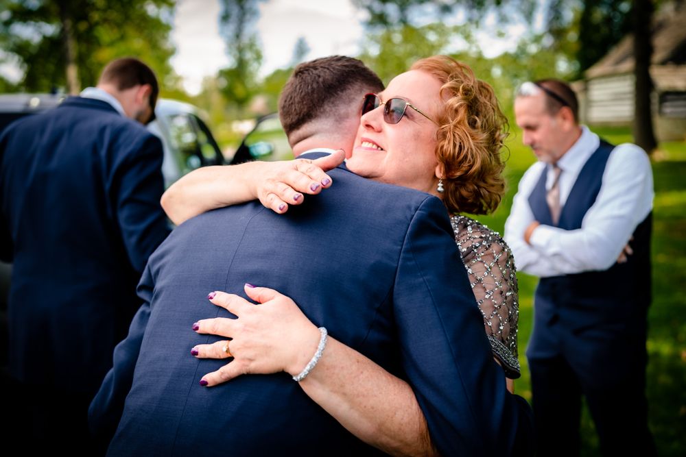 Candid moments of emotional embraces during outdoor wedding celebration.