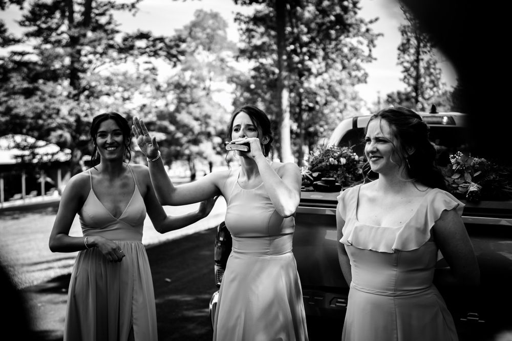 Wedding party in light colored dresses sharing joyful moments outdoors.