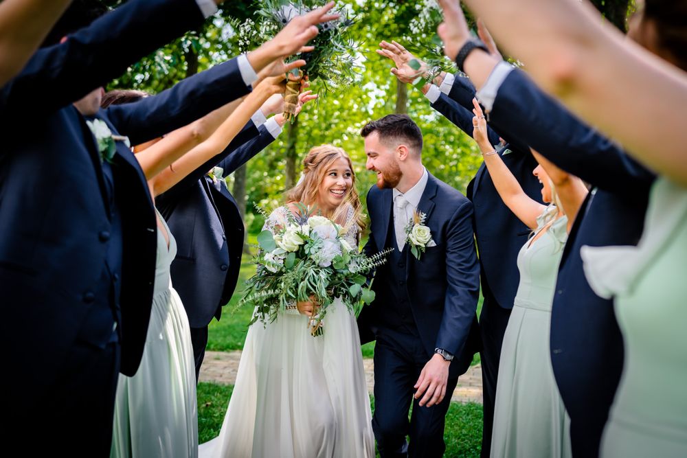 Wedding party members in formal attire celebrating with playful poses outdoors.