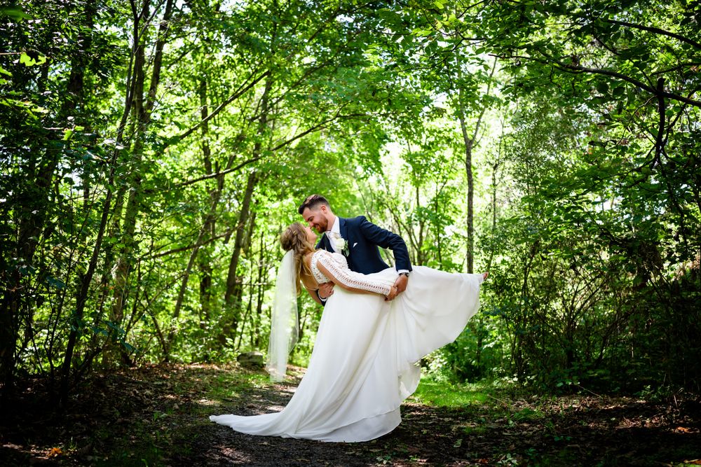 Wedding photography in a wooded area with natural sunlight filtering through green trees.