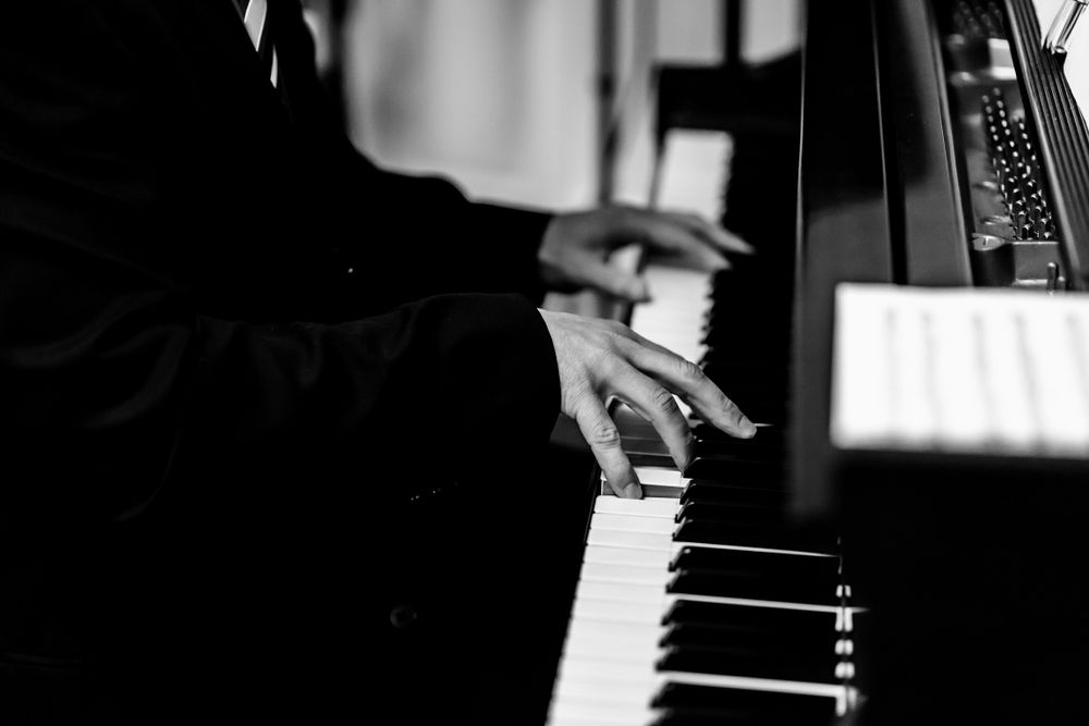 Close-up shots of hands playing piano keys in black and white.