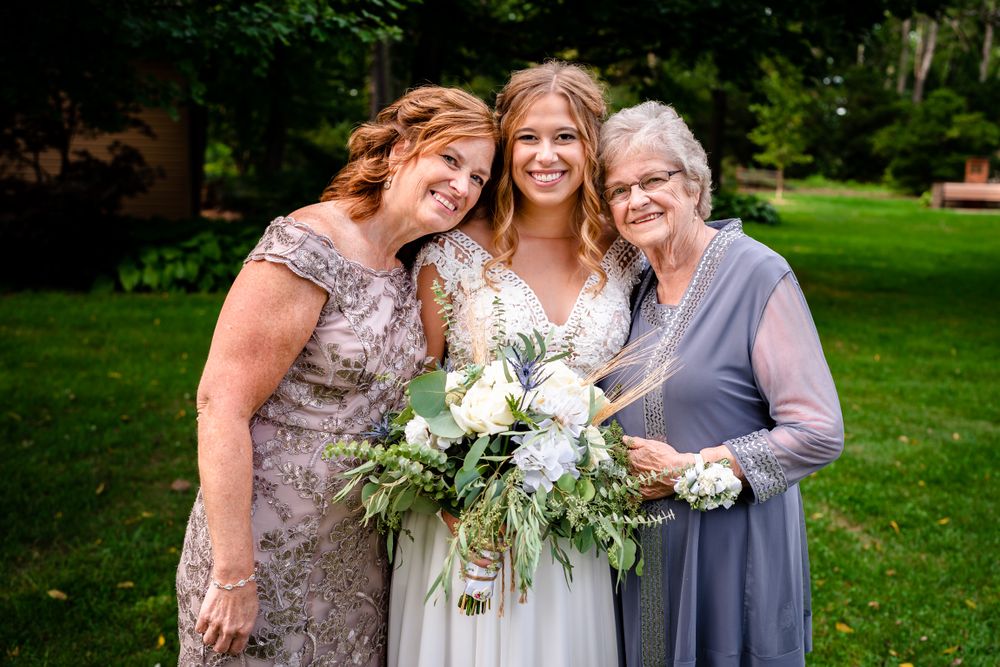 Wedding party members gather on a lush green lawn for outdoor group photos.