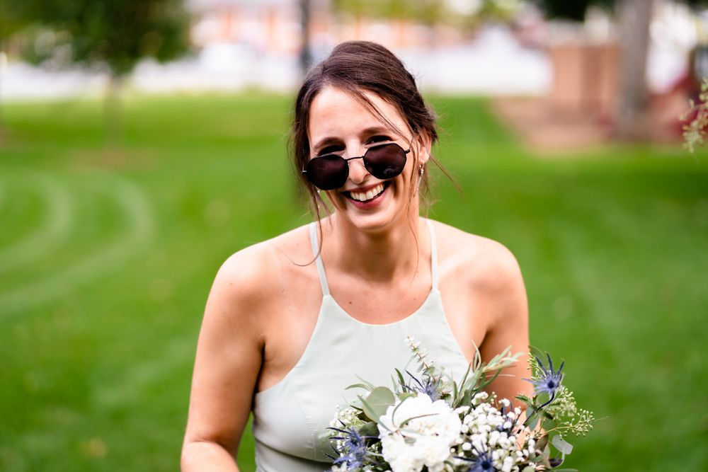 Wedding party poses for candid photos on a sunny lawn with natural greenery.
