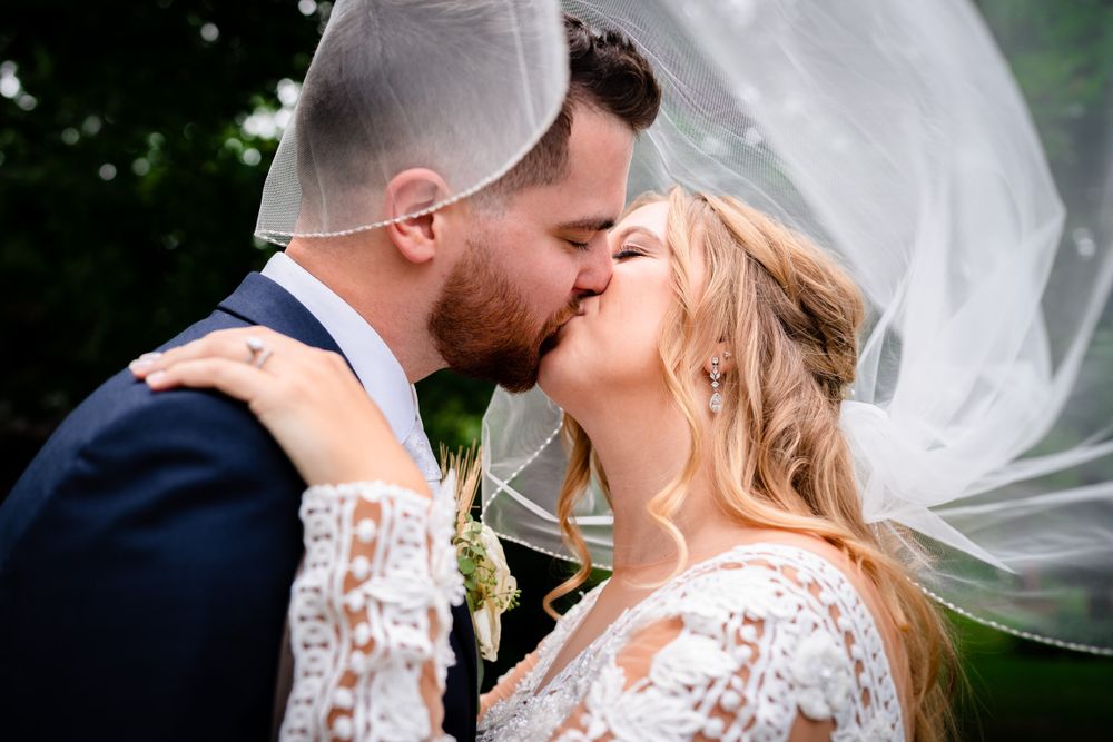 Romantic wedding portraits with flowing veil captured during an intimate outdoor moment.
