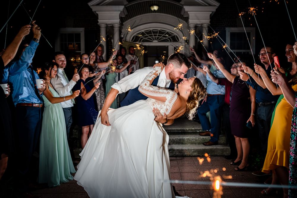 Couples dance and celebrate at a lively wedding reception on a dark dance floor with dramatic lighting.