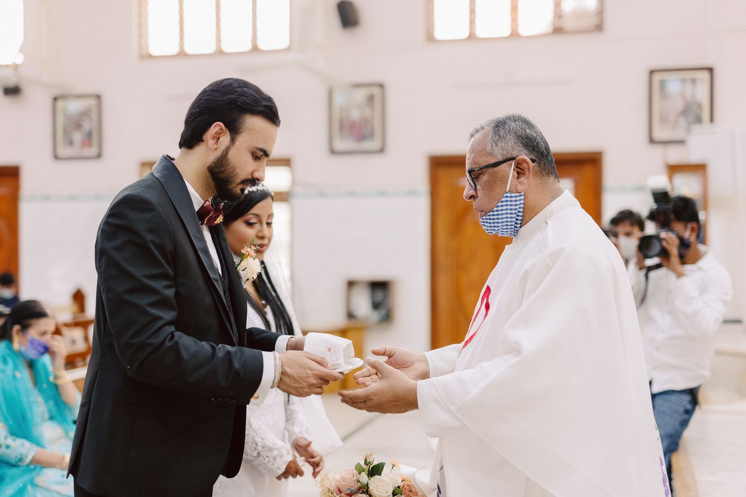 Wedding celebration inside a church with elegant white decor and wooden furnishings.
