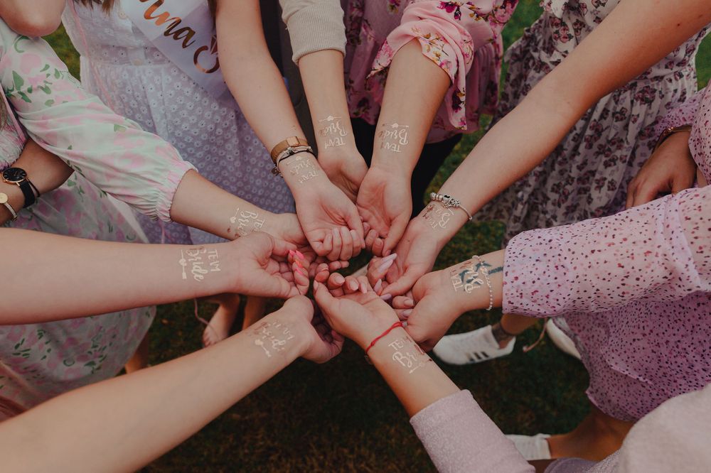 Friends joining hands in a circle during an outdoor celebration.