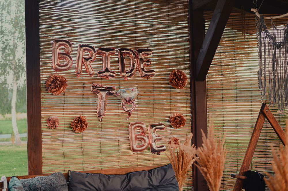 Rustic outdoor party setup with bamboo screens and pink balloon decorations.