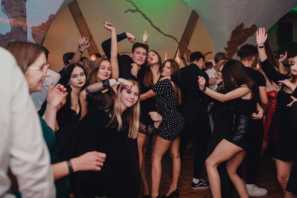 Crowd of people dancing and celebrating at a dimly lit party venue.