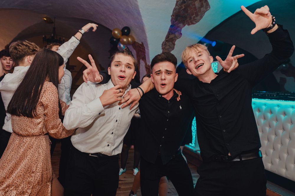 Energetic party scene with people dancing and jumping under atmospheric blue lighting.