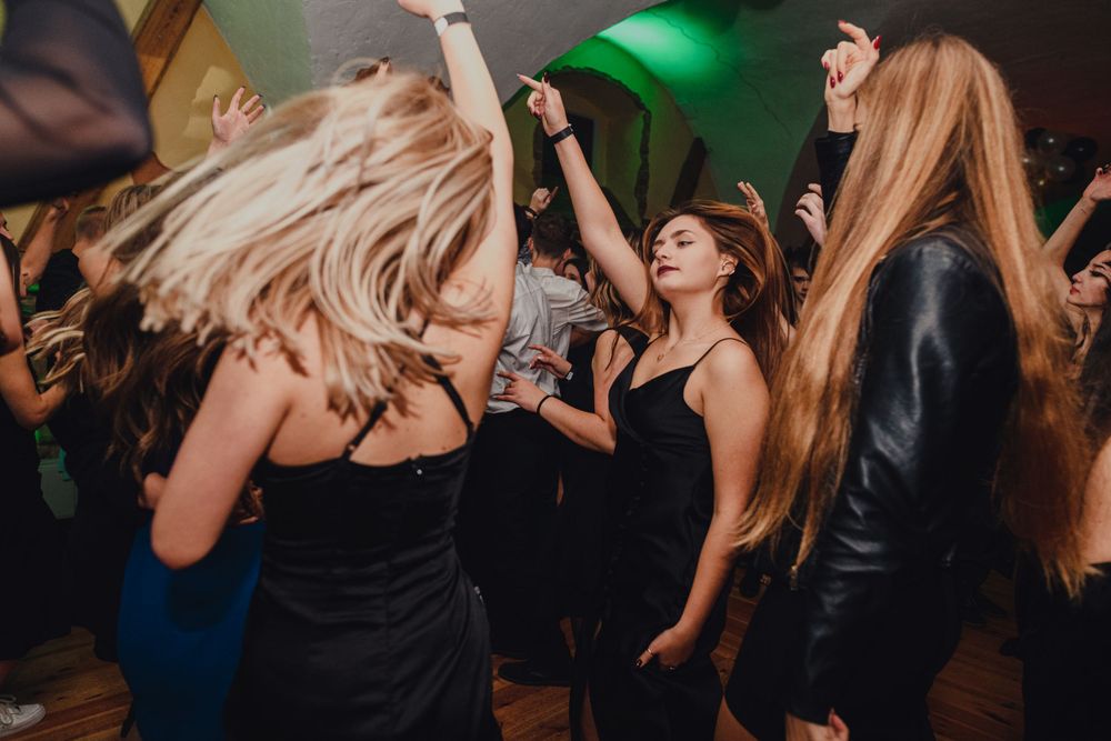 Lively dance party with people enjoying themselves under green and blue lighting effects.