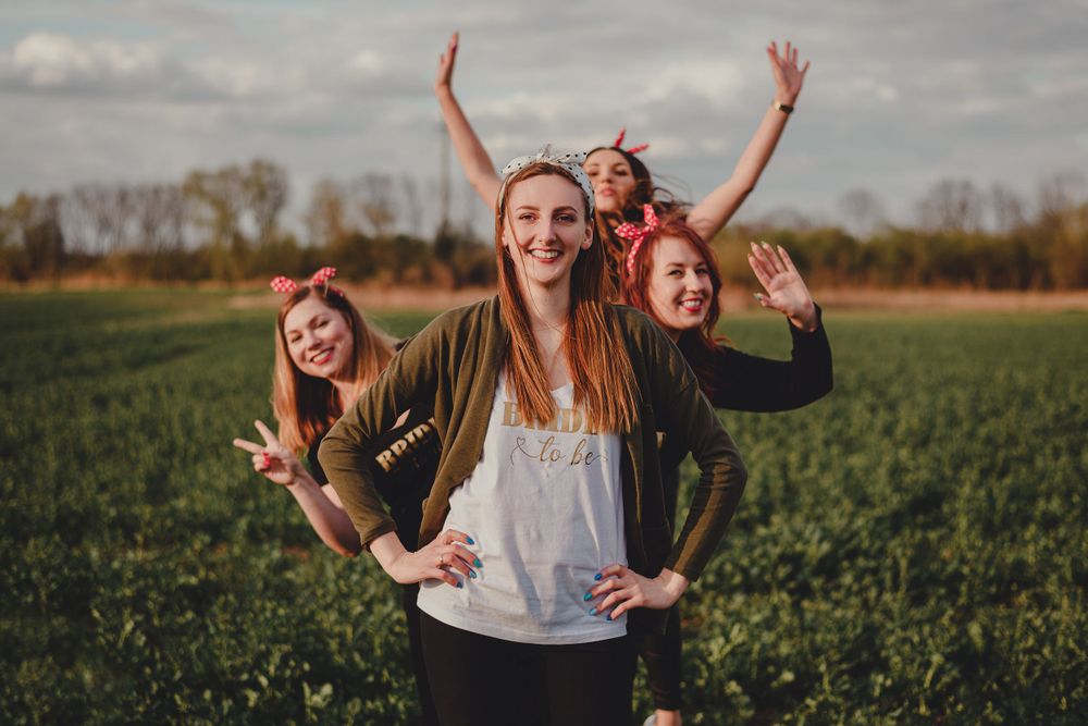 Joyful group posing and making peace signs in a green countryside field.