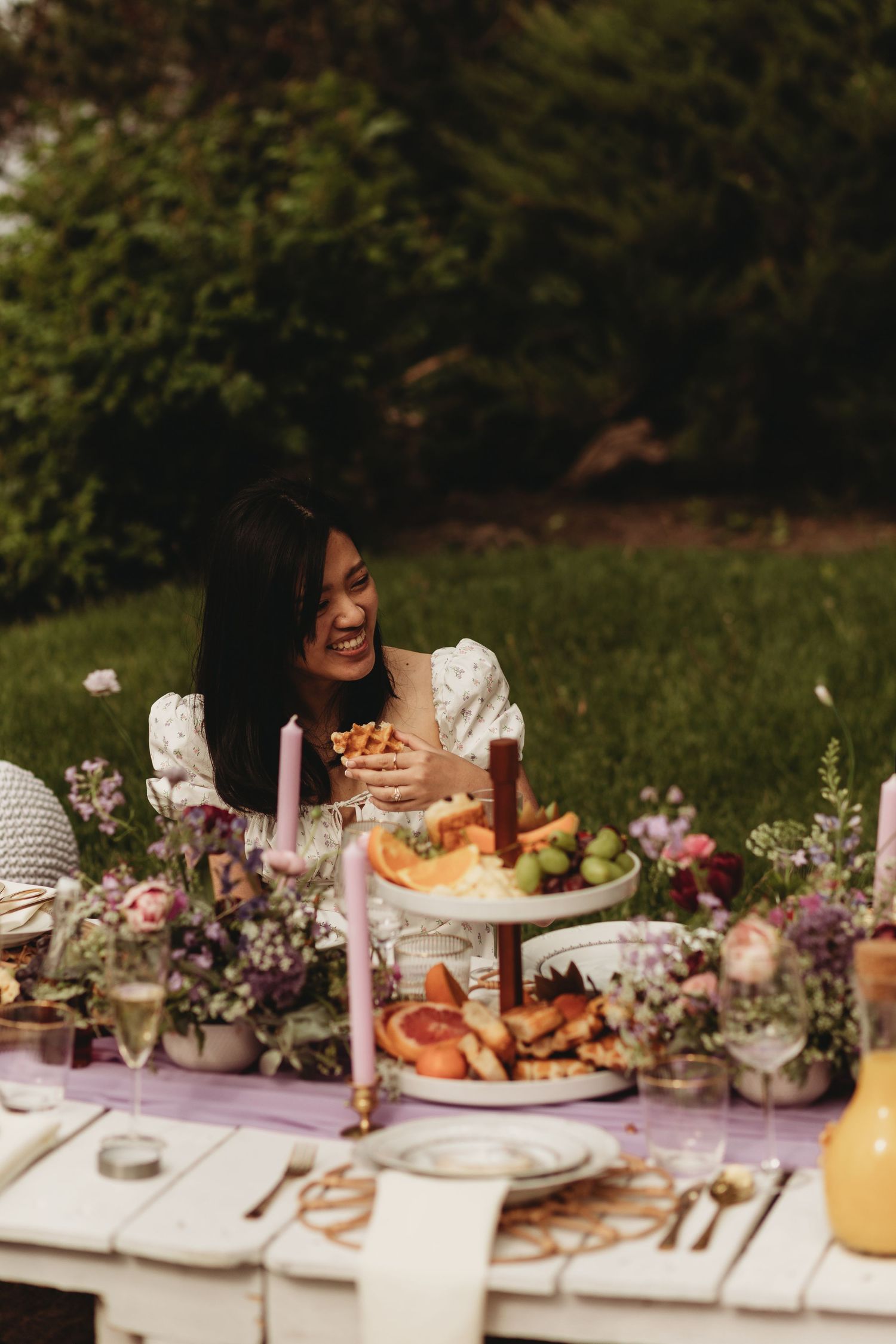 Elegant outdoor dinner setup with floral arrangements and tiered serving platters.