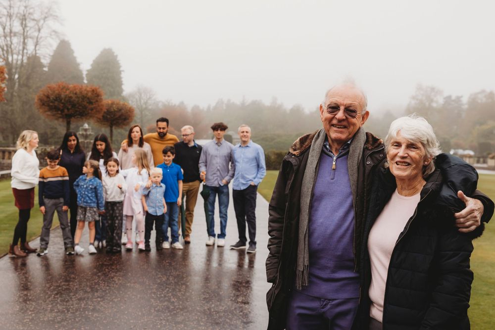 Extended family photo session on rainy day with large group in background.