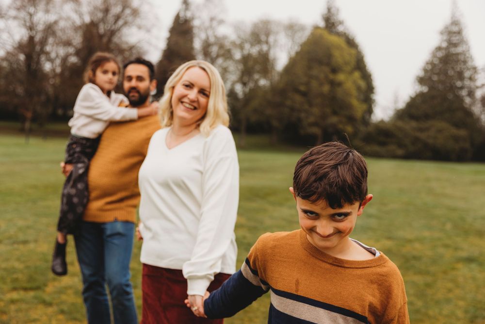 Family walking together outdoors in casual attire on a cloudy day.