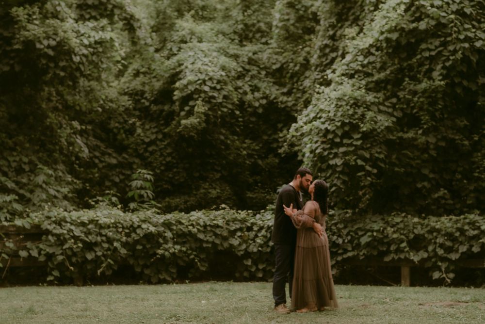 A distant shot of a couple embracing in a serene garden setting.