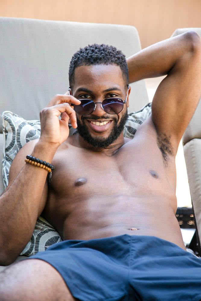 man relaxing at the pool peeking over the top of his sunglasses
