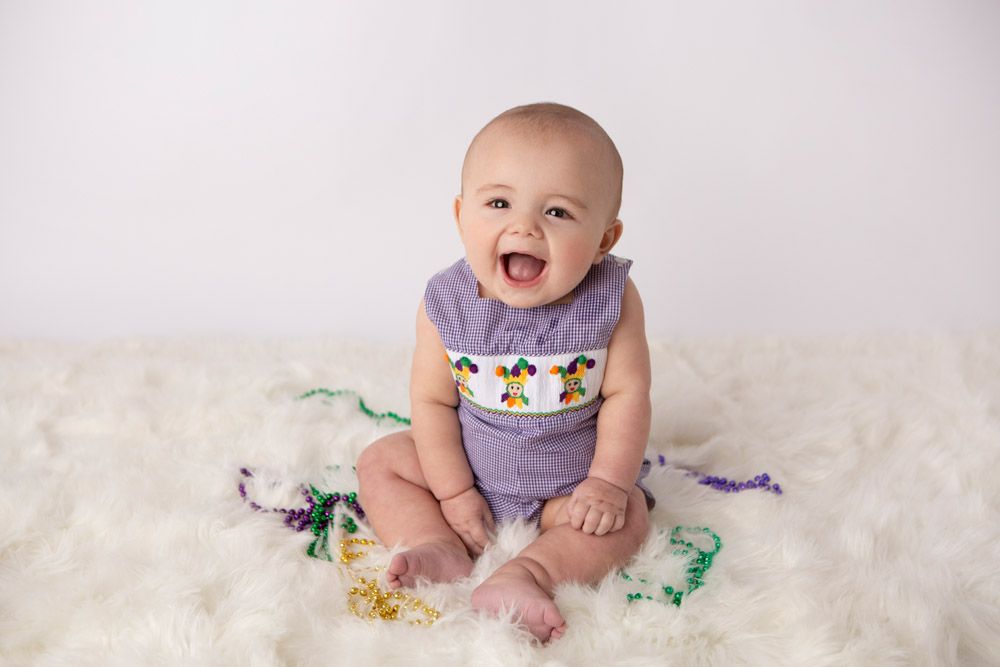 Happy moment captured on white fur backdrop with colorful toy dinosaurs.