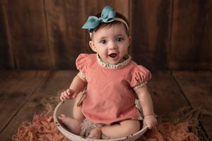 Baby in coral top with mint bow sitting in vintage bowl.