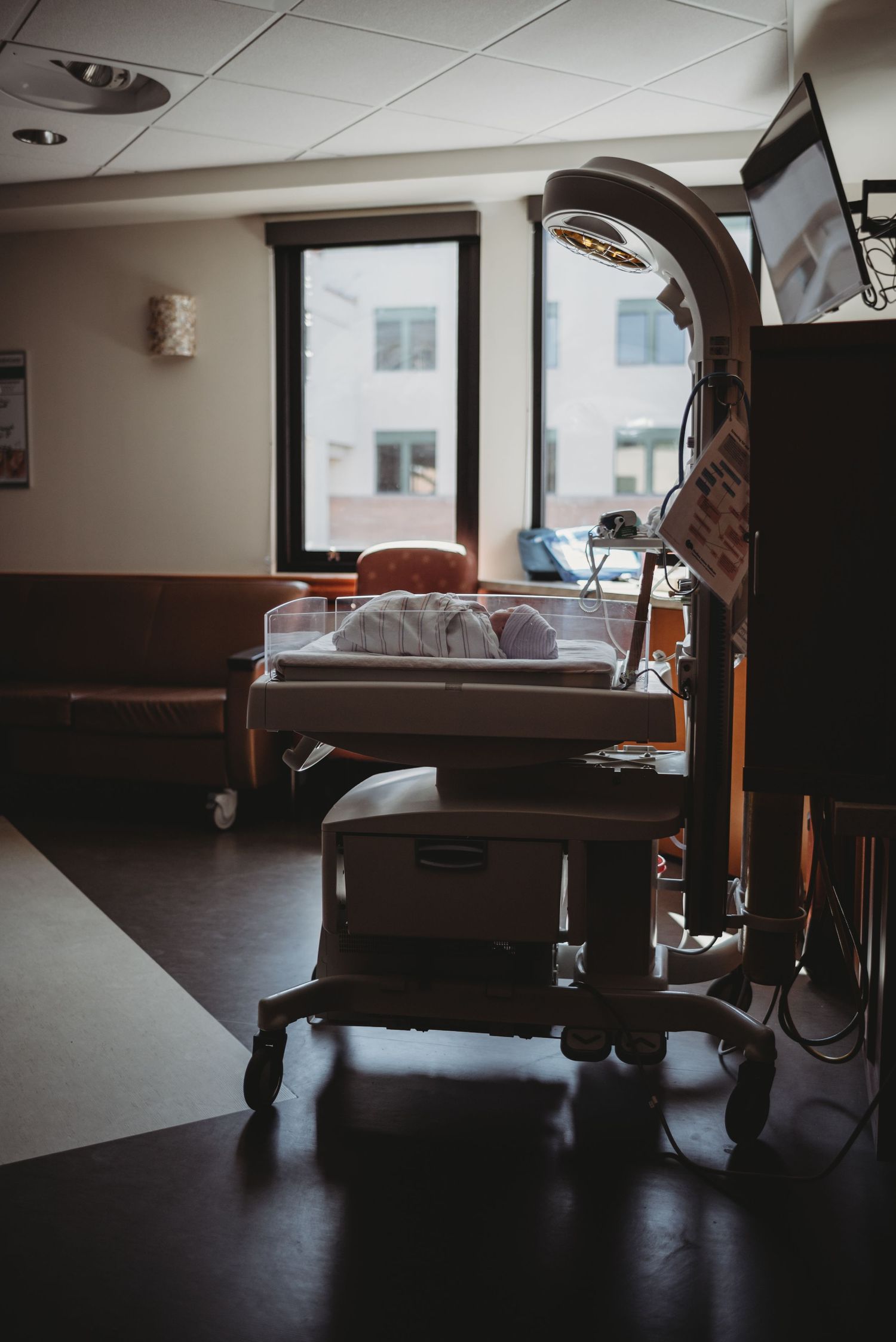 A dimly lit hospital room with an empty bed and medical equipment.