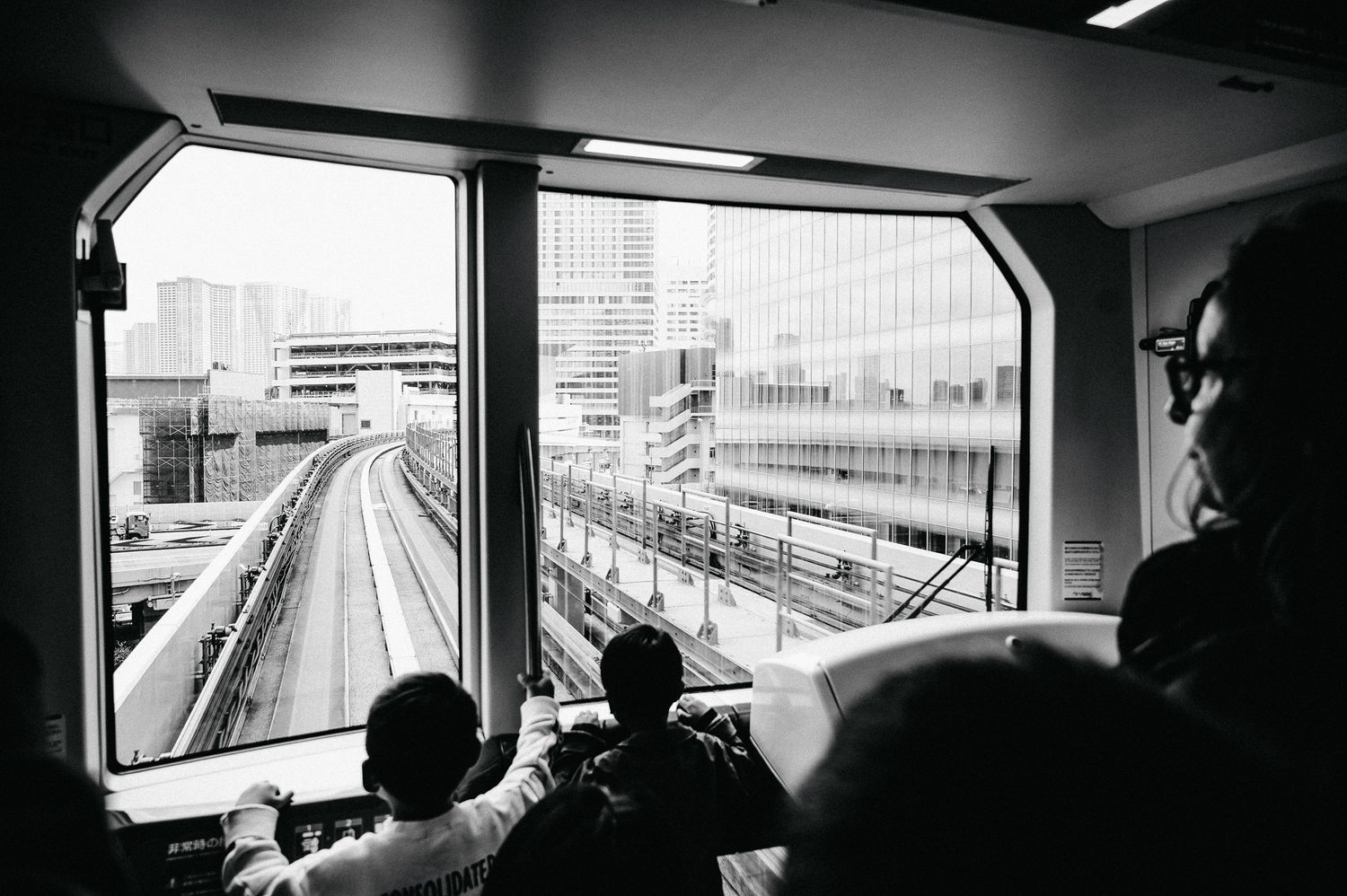 View from inside a Tokyo monorail car showing elevated tracks ahead.