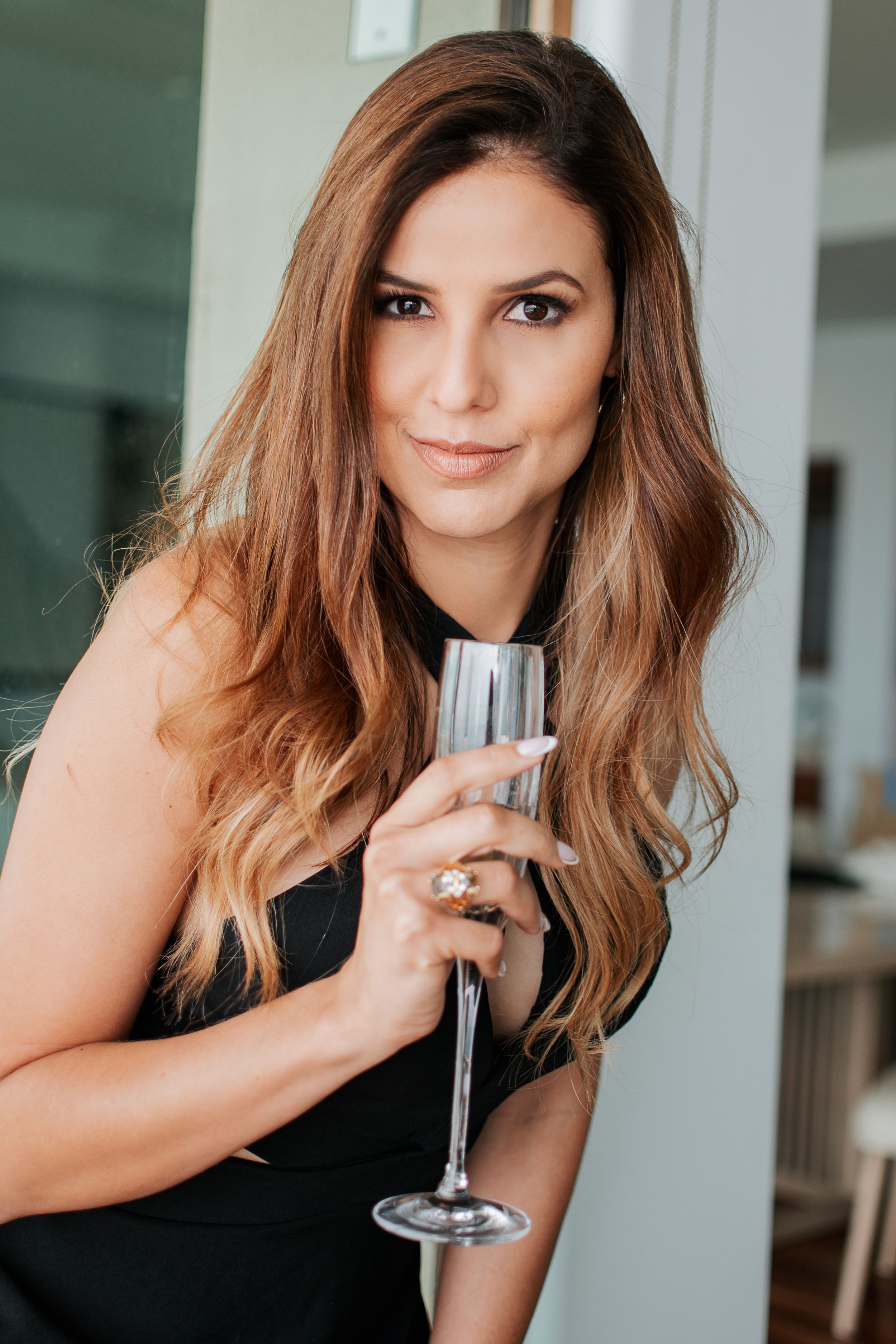 Lifestyle portrait with champagne glass against modern interior backdrop.