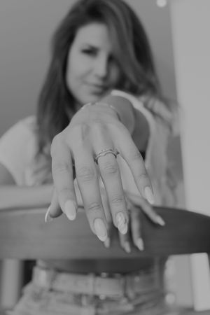 Black and white photo showing hand with engagement ring and manicured nails.