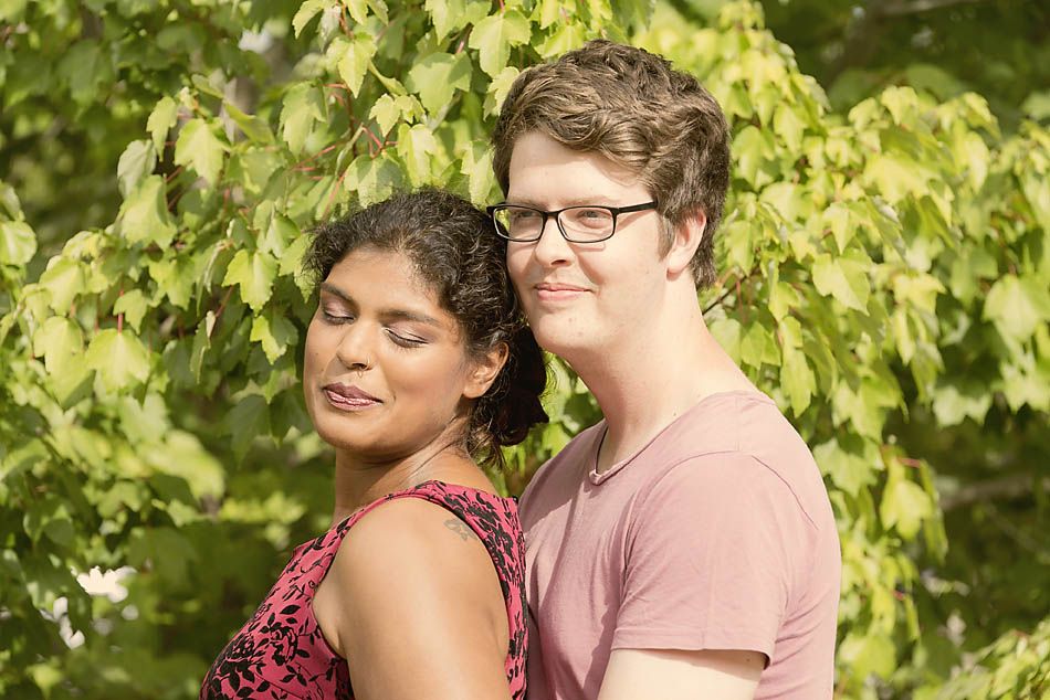 A romantic couple portrait against green foliage in summer attire.