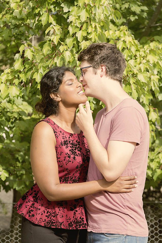 A tender romantic moment between a couple surrounded by green leaves.