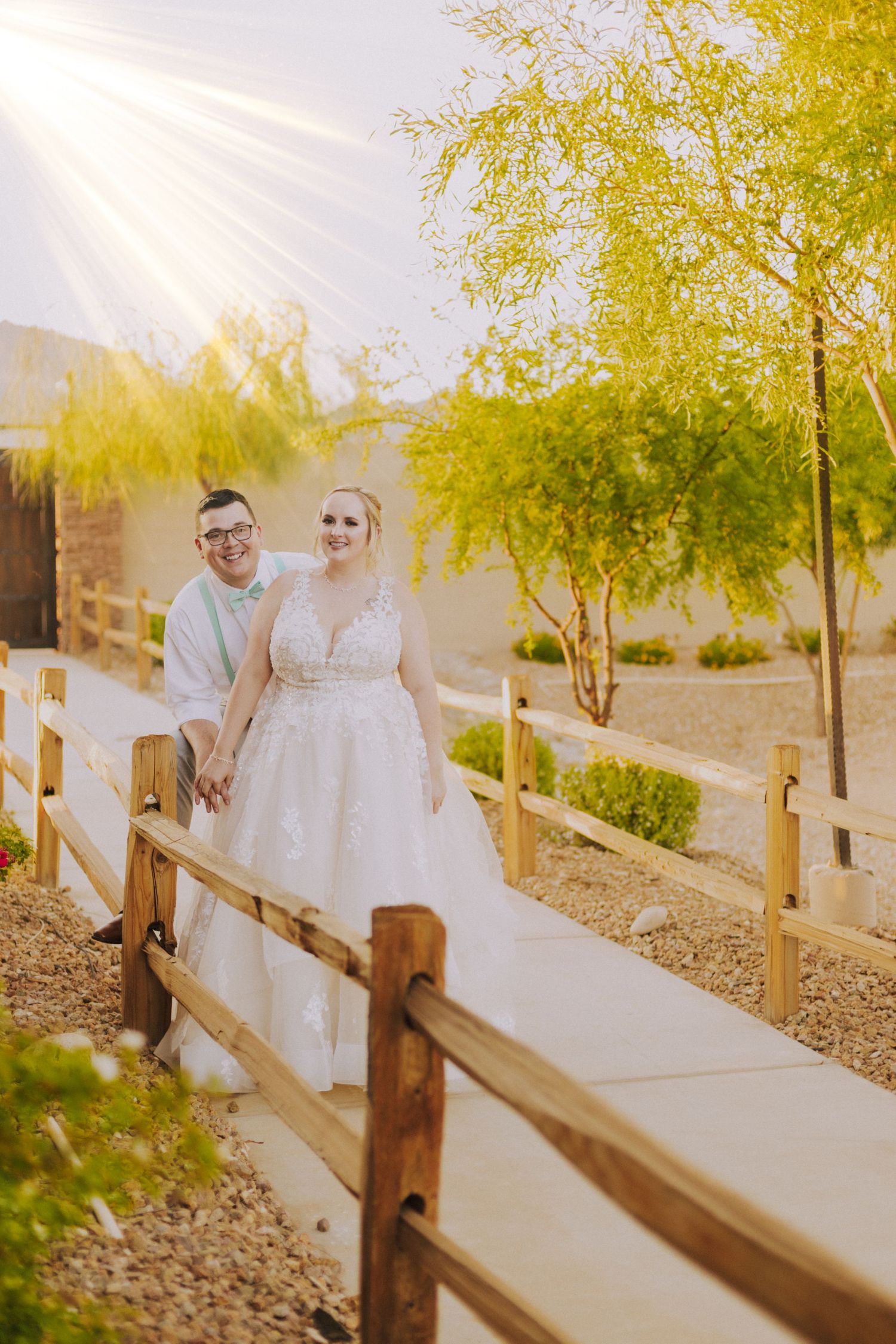 Sunlit pathway with wooden fence and yellow-leaved trees creating a warm, romantic outdoor setting.