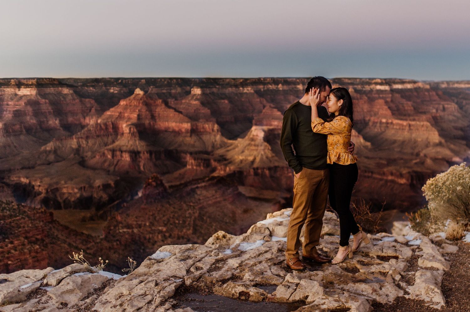 Couple embracing at sunset overlooking the majestic Grand Canyon landscape.