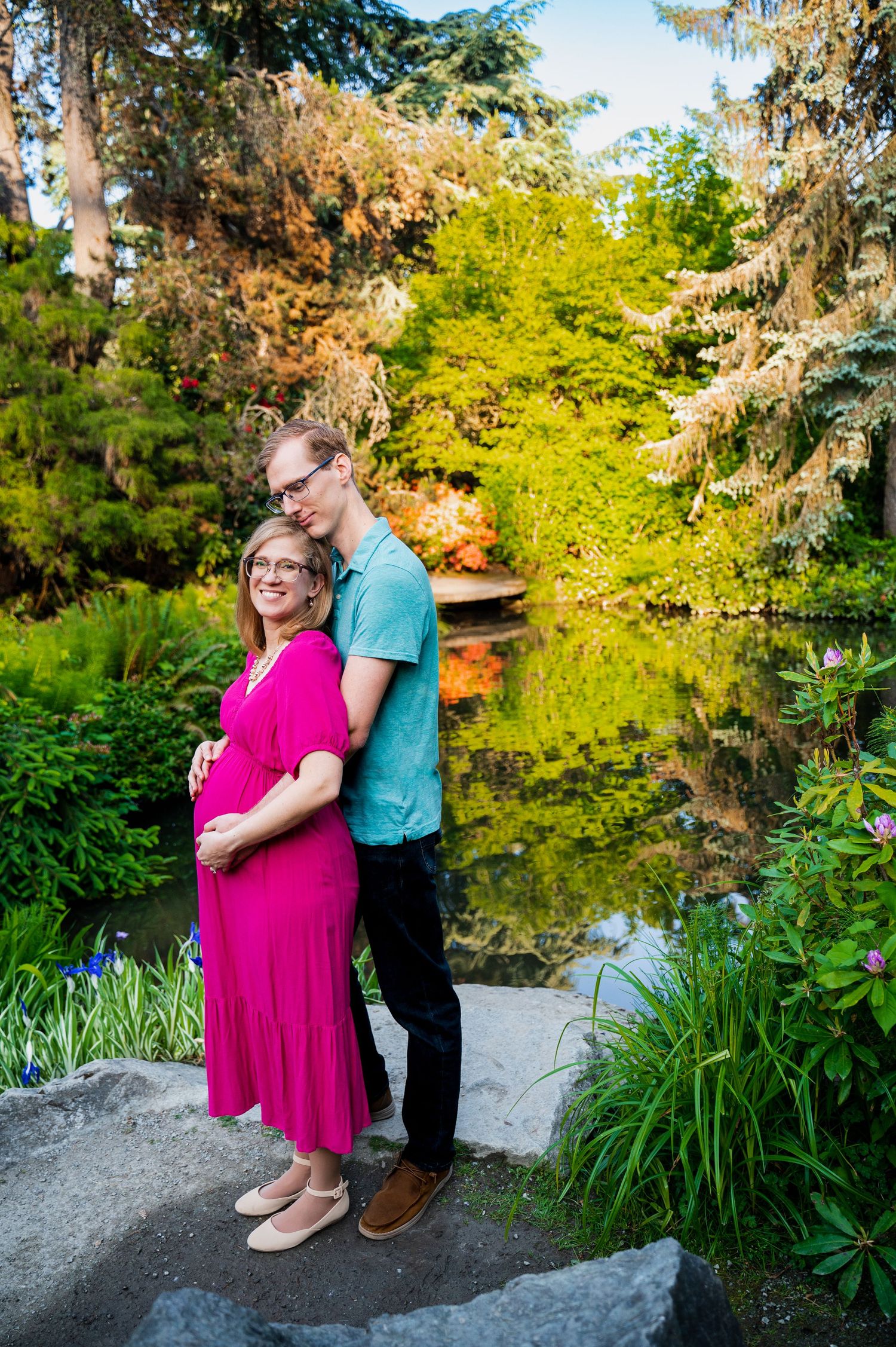 Young pregnant couple embraces at the beautiful Kabuto Gardens in Seattle WA, for a Redmond Photographer.
