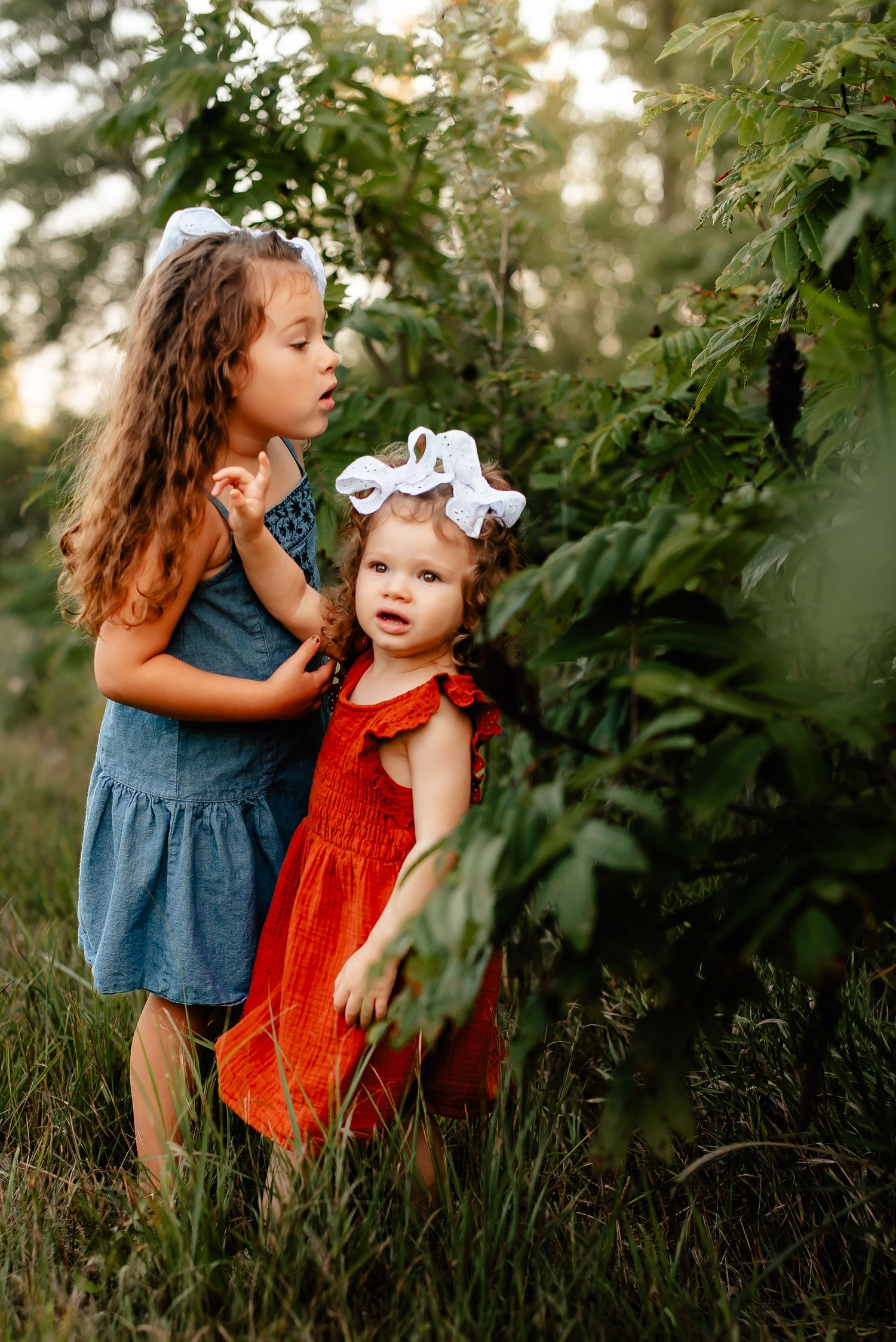 Two children exploring nature together in a green outdoor setting.
