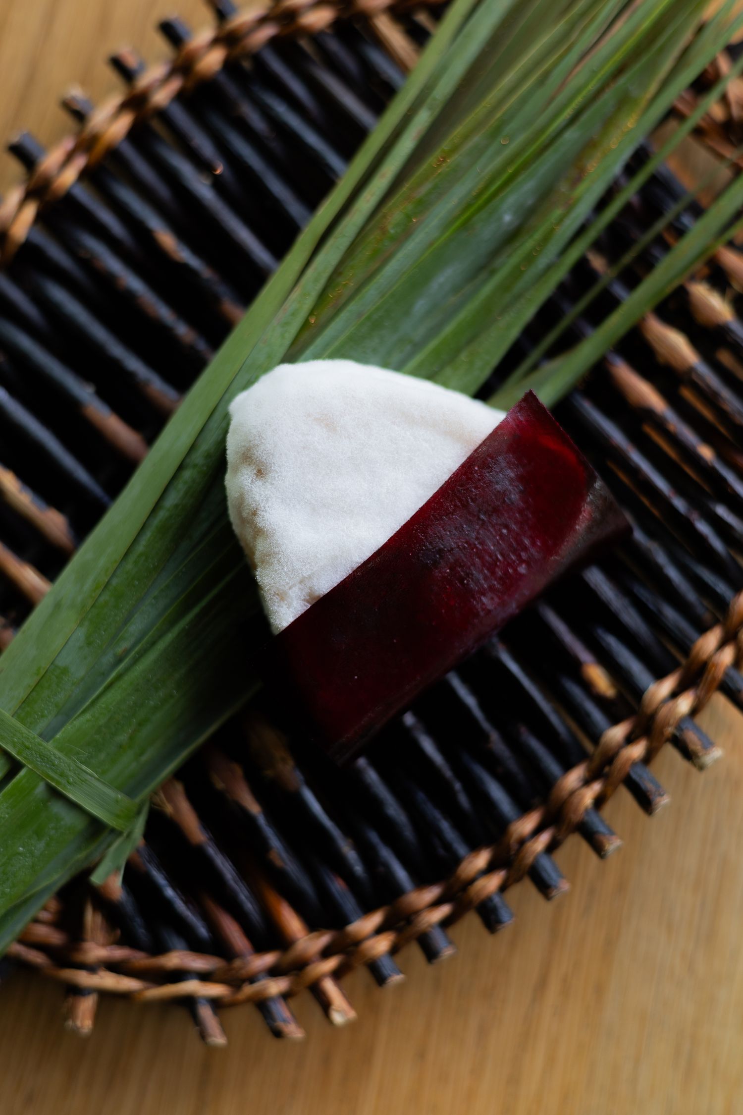 Half white and red garnish placed on green bamboo leaves on a woven dark platter.