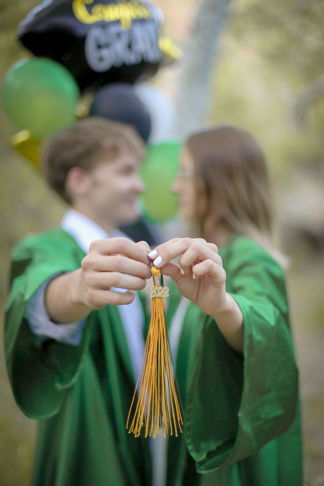 Portrait of a senior boy and girl holding their tassle together in the foreground