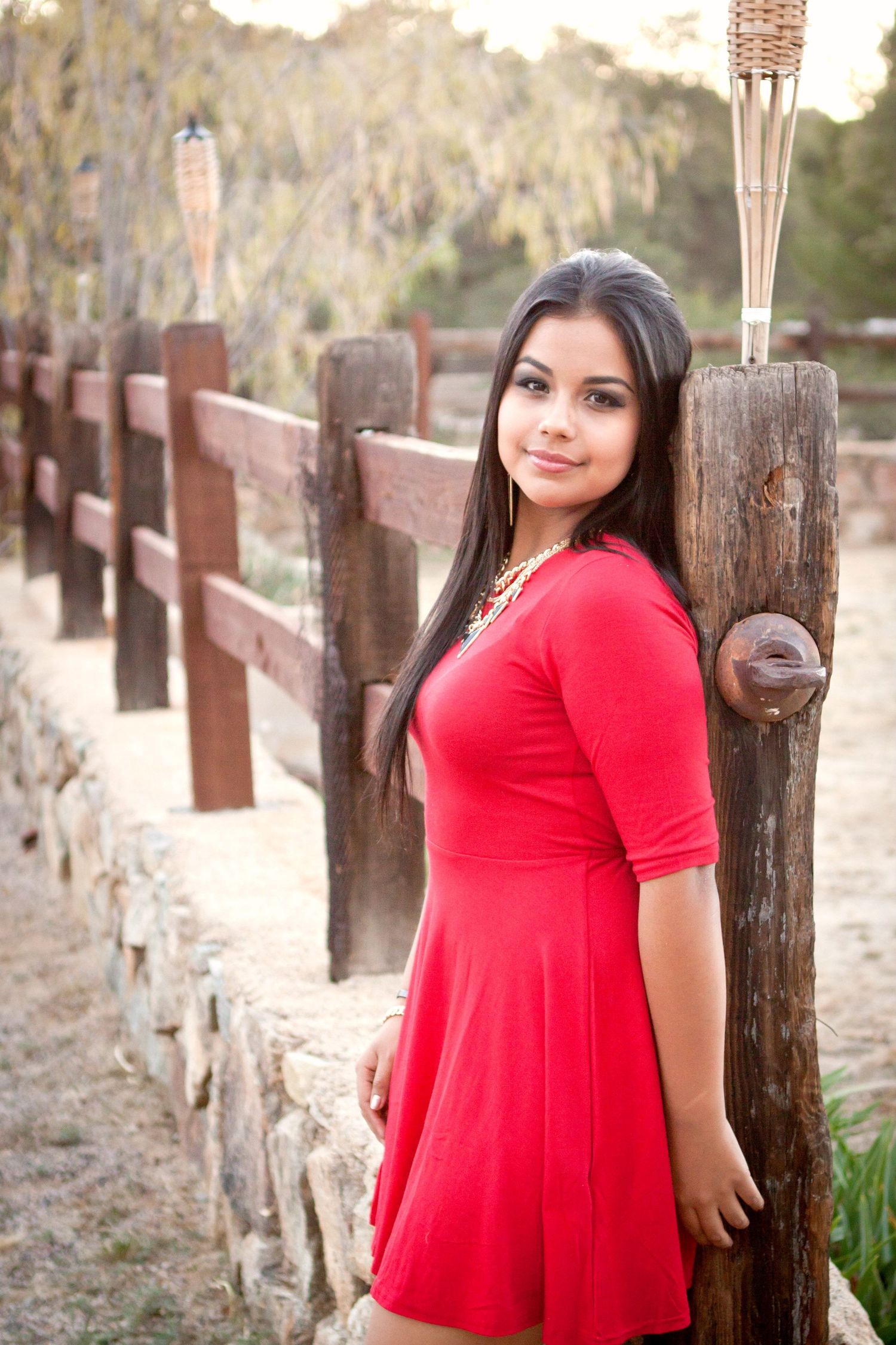 Portrait of a senior girl leaning against a wooden fence post