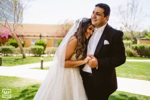 Newlyweds share a tender moment while posing on manicured lawn during their wedding.