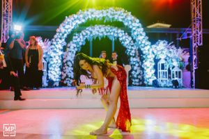 Couple dancing under illuminated floral arches at their wedding reception.